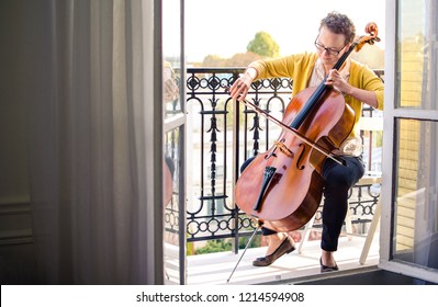 Female classical musician playing cello on a balcony in Paris