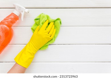 Female cleaner hand in yellow glove cleaning surface with duster.