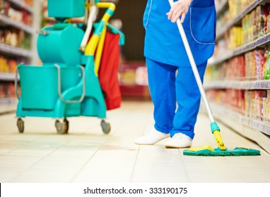 Female Cleaner Worker In Uniform  With Mop Cleaning The Floor Of Supermarket Shop Store