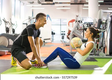 Female client doing abdominal crunches with ball while her personal trainer assisting her. - Powered by Shutterstock