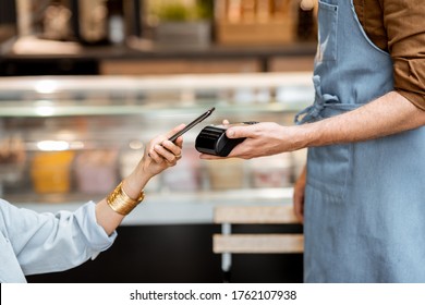 Female client paying by phone contactlessly at the cafe, close-up - Powered by Shutterstock