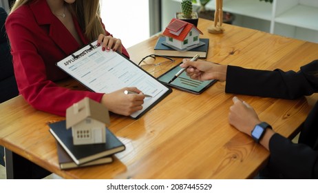 A Female Client Signs A Rental Application Form For A New House. Real Estate Agent Meets With Her Potential Client.