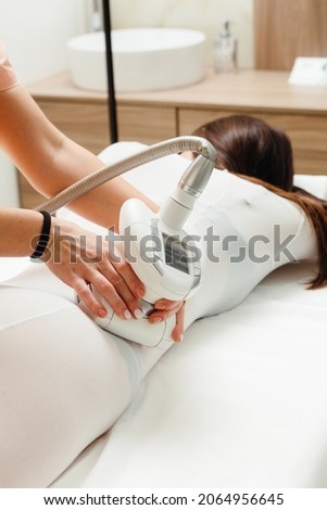 Female client in white suit lying an her tomach, getting LPG massage in a spa