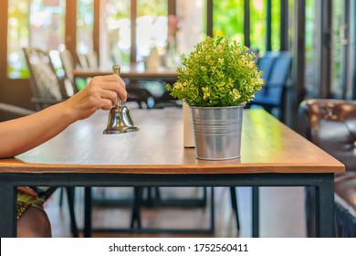 The female client's right hand hold a small bell to shake for call the waiter in coffee shop.