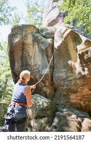 Female Climber Belaying Leader During Rock Climbing Outdoors, Using Rope And Carabines. Back View Of Elderly Woman Looking To His Rope Partner. Concept Of Extreme Sport And Outdoor Activity.