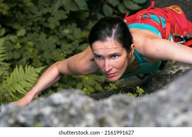 Female climber with brown hair lead climbing limestone rock in German Frankenjura. Searching for next hold in tensed position, looking across the frame - Powered by Shutterstock