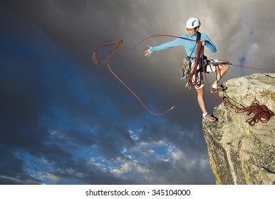 Female Climber Dangles From The Edge Of A Challenging Cliff.