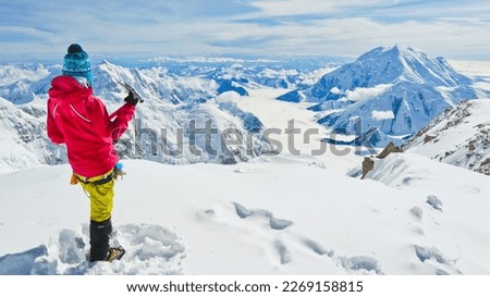 A female climber with ice axe enjoying panoramic view on Mt Denali in Alaska, the highest mountain in North America