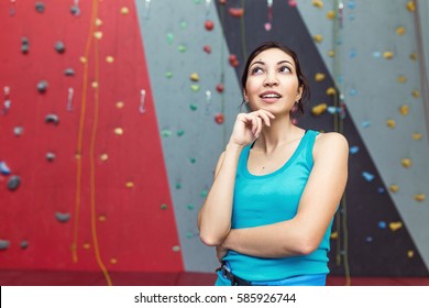 Female climber looking and thinking on artificial climbing wall background - Powered by Shutterstock