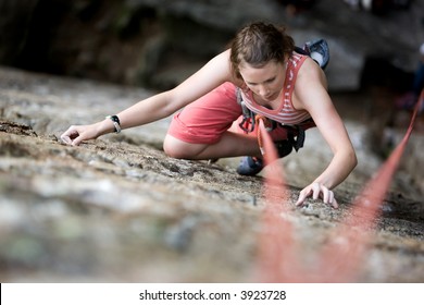 A female climber on a steep rock face viewed from above with the belayer in the background.  Shallow depth of field is used to isolated the climber. - Powered by Shutterstock