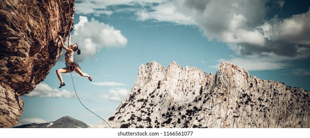 Female climber struggeling up a sheer cliff. - Shutterstock ID 1166561077