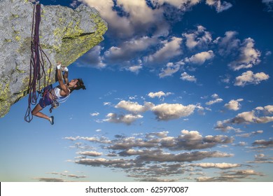 Female climber struggeling up a sheer cliff. - Shutterstock ID 625970087