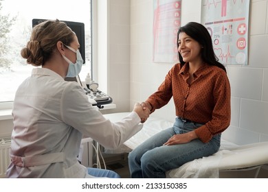 Female clinician shaking hand of young happy Hispanic patient sitting on couch in medical office after ultrasound examination - Shutterstock ID 2133150385