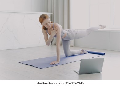 Female Coach Explaining At Video Class. Young Athlete Practicing Yoga By Video Lessons In Her Apartment. White Woman Doing Posture Exercise. Concept Of Personal Training And Remote Work.