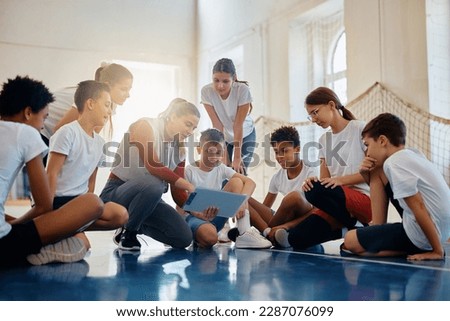 Female coach and group of kids analyzing game plan during PE class at school gym. Stock photo © 