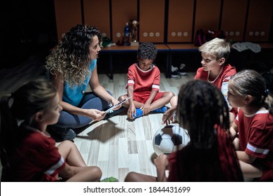 A female coach and her little players at the locker room discussing strategy for the match. Children team sport - Powered by Shutterstock