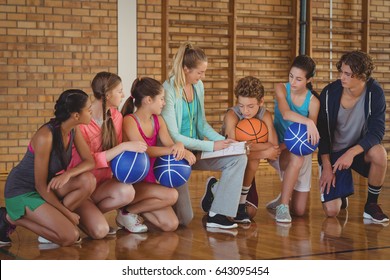 Female Coach Mentoring High School Kids In Basketball Court