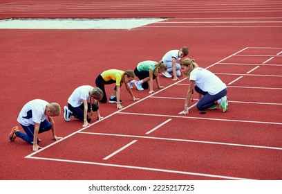 Female coach training athletes. Start. Group of children preparing to run on treadmill at the stadium. Concept of sport, achievements, studying, goals, skills. Little boys and girls training outdoor. - Powered by Shutterstock