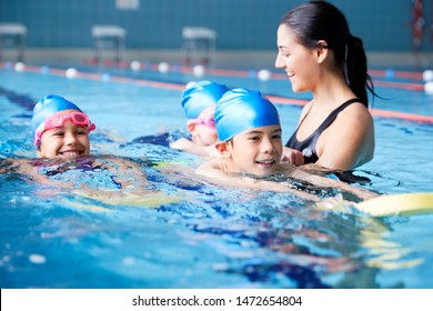 Female Coach In Water Giving Group Of Children Swimming Lesson In Indoor Pool - Powered by Shutterstock