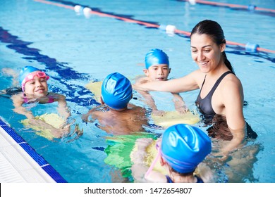 Female Coach In Water Giving Group Of Children Swimming Lesson In Indoor Pool - Powered by Shutterstock
