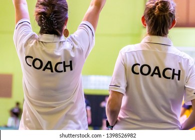 Female coaches in white COACH shirt at an indoor sport game - Powered by Shutterstock