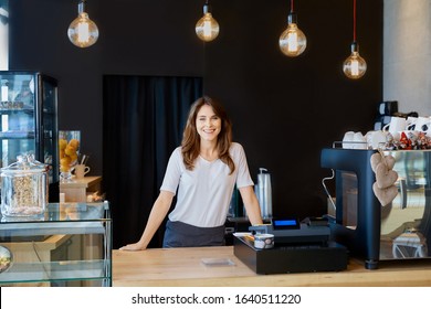 Female coffee shop owner standing behind a bar counter