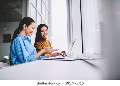 Female colleagues smiling in coworking office cooperating using laptop computers for online browsing, cheerful employees discussing media content during brainstorming programming and networking - Powered by Shutterstock