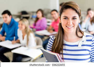 Female College Student In A Classroom Holding A Notebook