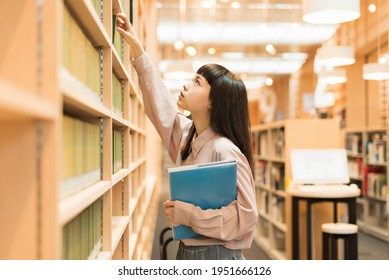 Female college student looking for a book in the library - Powered by Shutterstock