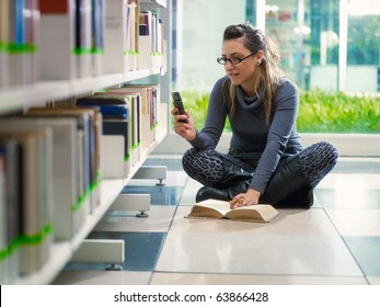 Female College Student Sitting On Floor In Library, Typing On Mobile Phone. Horizontal Shape, Front View, Full Length, Copy Space