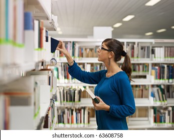 Female College Student Taking Book From Shelf In Library. Horizontal Shape, Side View, Waist Up, Copy Space