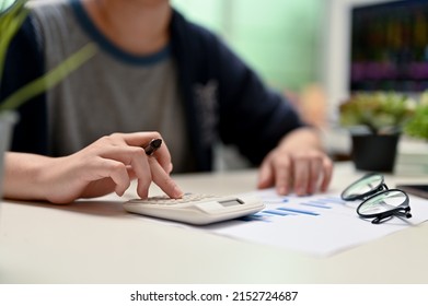 Female College Student Using Calculator, Doing Her Financial Homework At Her Home Workspace. Cropped