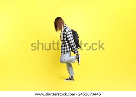 A female college student wearing plaid shirt while carry school bag with gesture of standing. Education, Studying abroad, Gen Z, E-learning. Teenager.