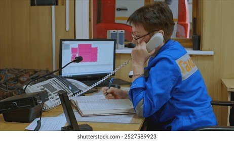 Female company administrator is sitting at desk. Clip. Woman in company uniform is sitting at administrator's desk. Woman at entrance to factory - Powered by Shutterstock