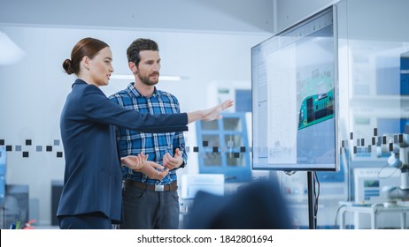 Female Computer Engineer And Male Project Manager Use Digital Interactive Whiteboard That Shows 3D Printed Circuit Board Concept. Developers Find Problem Solution. Modern Factory Meeting Room