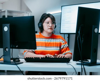 Female Computer Programmer working on Computer Writing and Developing Software Program, App looking at Dual screens in Creative Office workspace. Focused Professional female software developer work.