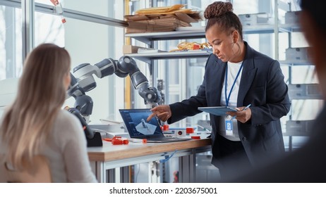 Female Computer Science Specialist Focused On Intersting Lecture By African American Professor. Diverse Group Of Young Engineers Programming Robotic Hand. Advanced Robotics Class Concept.