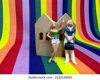 Female comrades standing in front of a house with a rainbow background; LGBT and homosexual family concept.