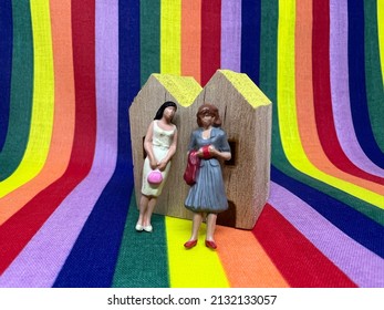 Female comrades standing in front of a house with a rainbow background; LGBT and homosexual family concept.