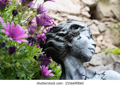 Female concrete sculpture with purple flowers 