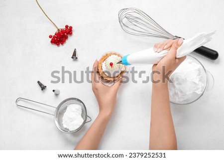 Female confectioner decorating tasty cake on white background