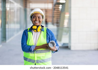 Female construction engineer. Architect with a blueprints at a construction site. Young Woman look in camera, building site place background. Portrait of adult female builder, engineer, architect - Shutterstock ID 2048113541