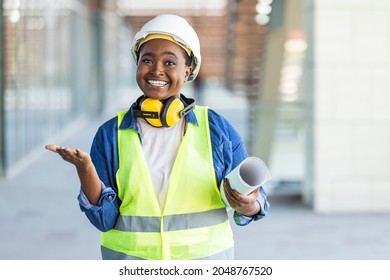 Female construction engineer. Architect with a blueprints at a construction site. Young Woman look in camera, building site place background. Portrait of adult female builder, engineer, architect