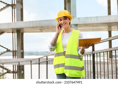 Female Construction Worker With Folder Talking By Mobile Phone Outdoors