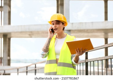 Female Construction Worker With Folder Talking By Mobile Phone Outdoors