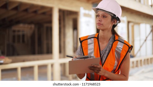 Female Construction Worker In Hardhat Uses On Clipboard At Residential Job Site