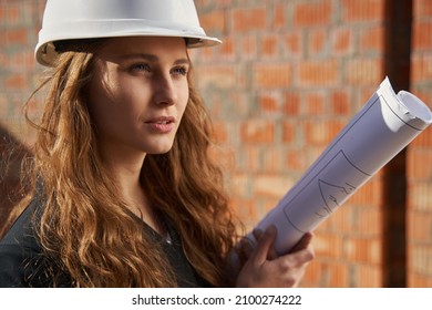 Female Construction Worker In Helmet Holding Blueprints