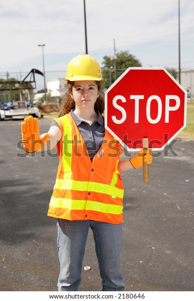 A female\
construction worker holding a stop\
sign.