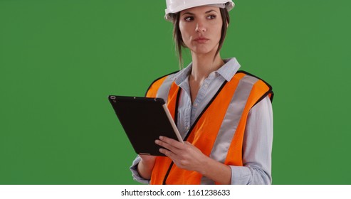 Female construction worker in orange vest and hard hat using pad on green screen - Powered by Shutterstock