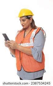 Female constructor using cell phone. Wearing hardhat and worker apron while isolated on white studio background.